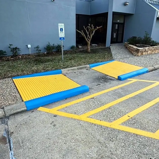 Accessible curb ramps painted yellow and blue with striped aisle