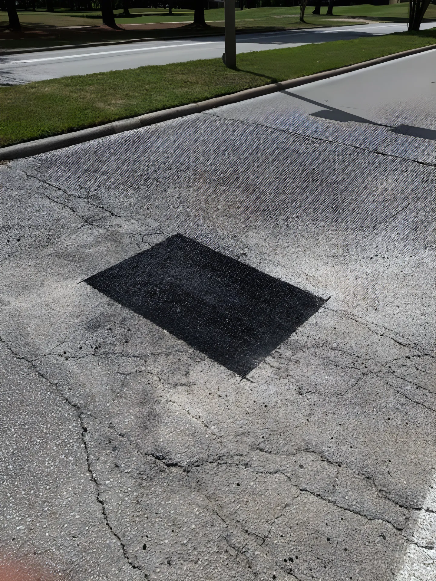 Asphalt patch repair compacted into damaged pavement