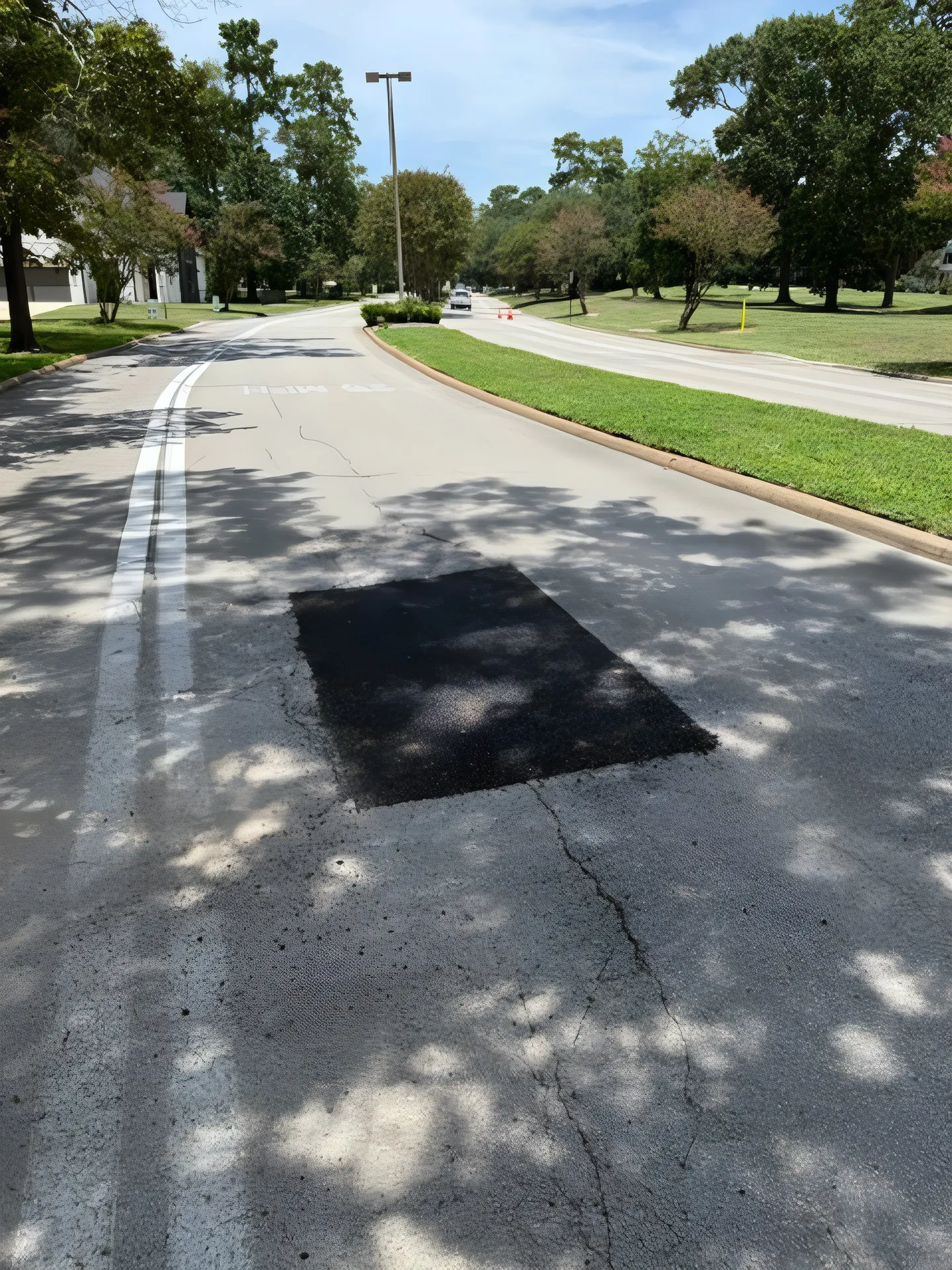 Fresh black asphalt patch set into faded grey pavement