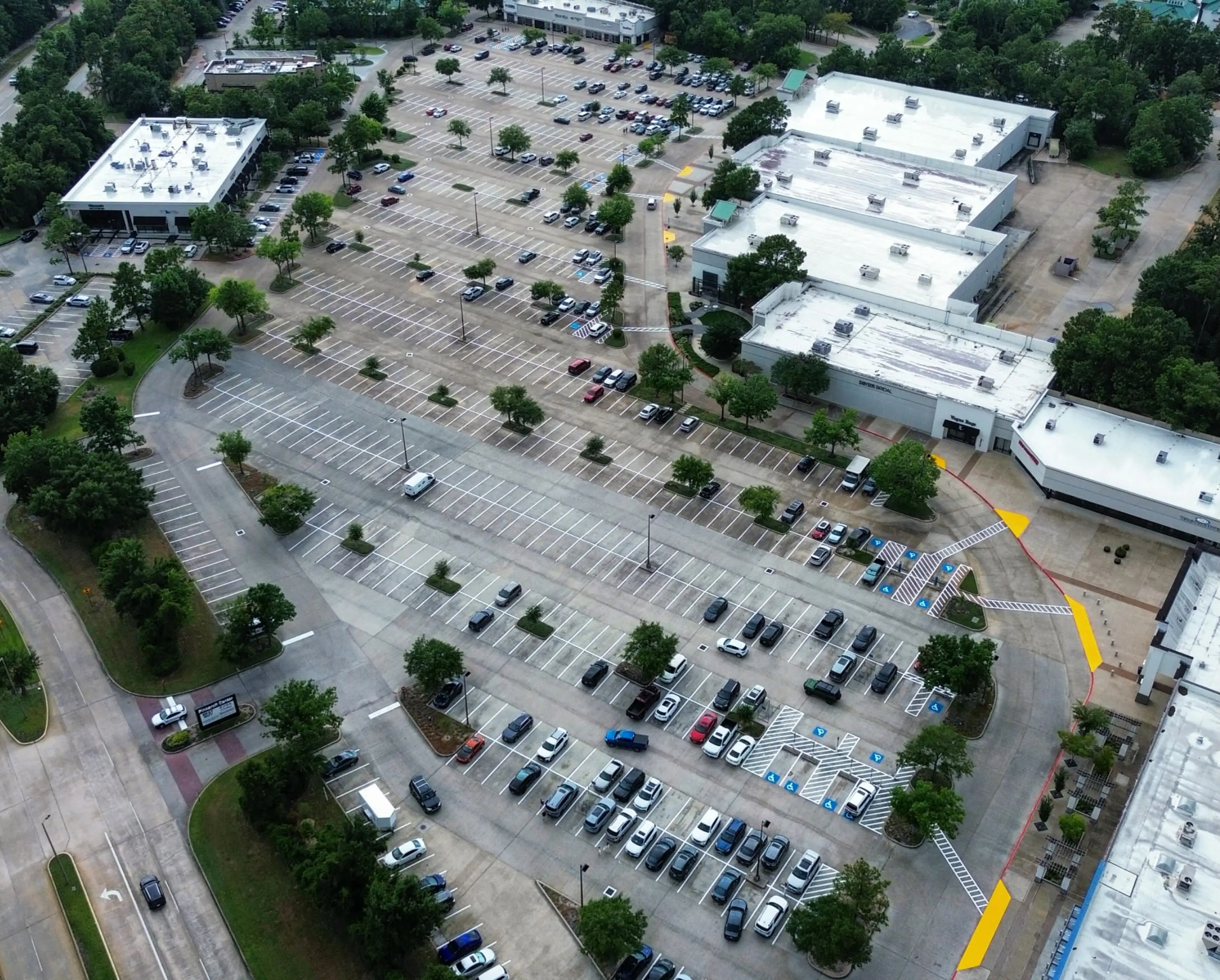 Aerial of a campus parking lot with new stripes and yellow curb at the entrance
