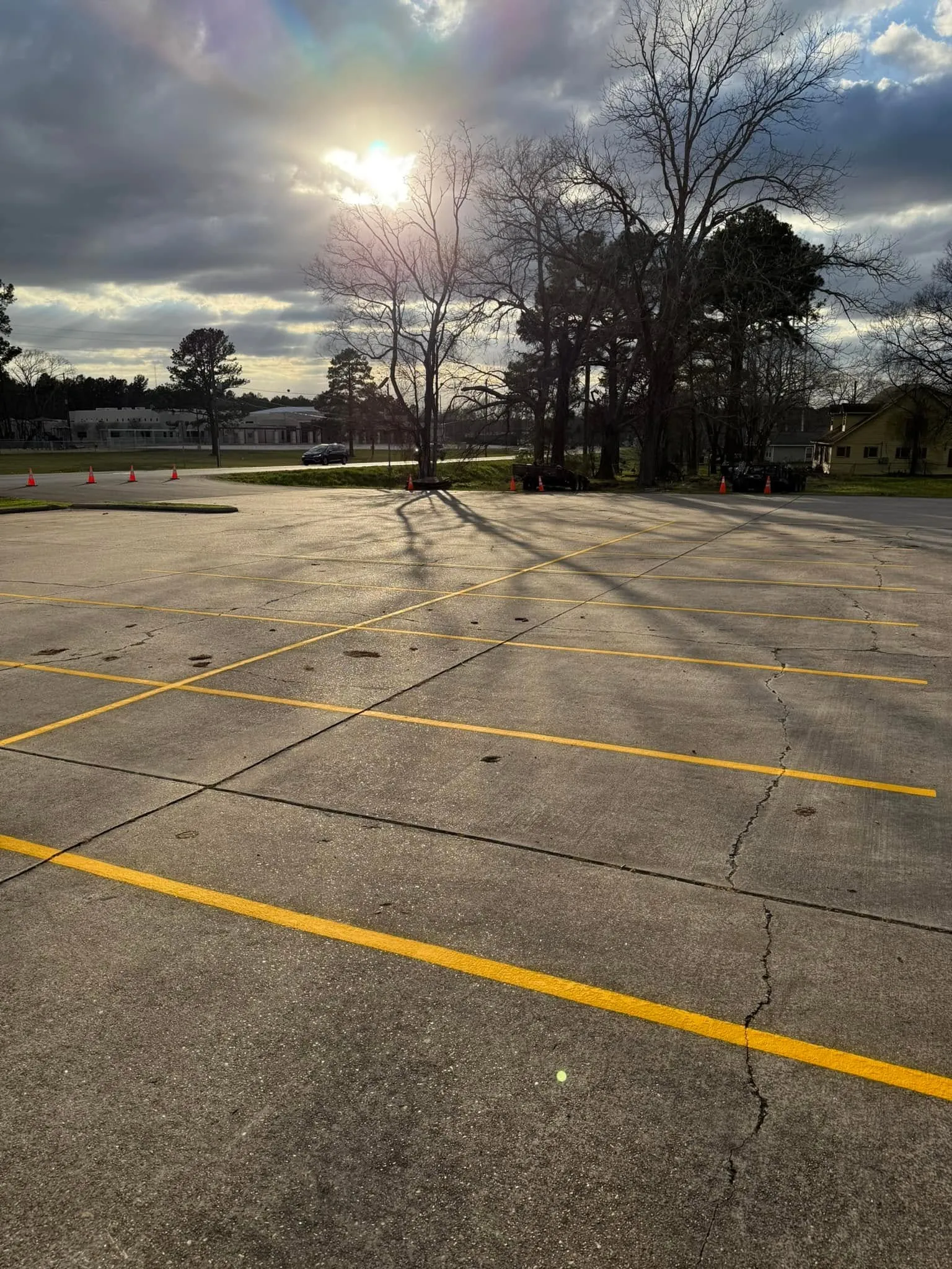 Cracked concrete parking lot with fresh yellow stall lines — the cracks are what we seal