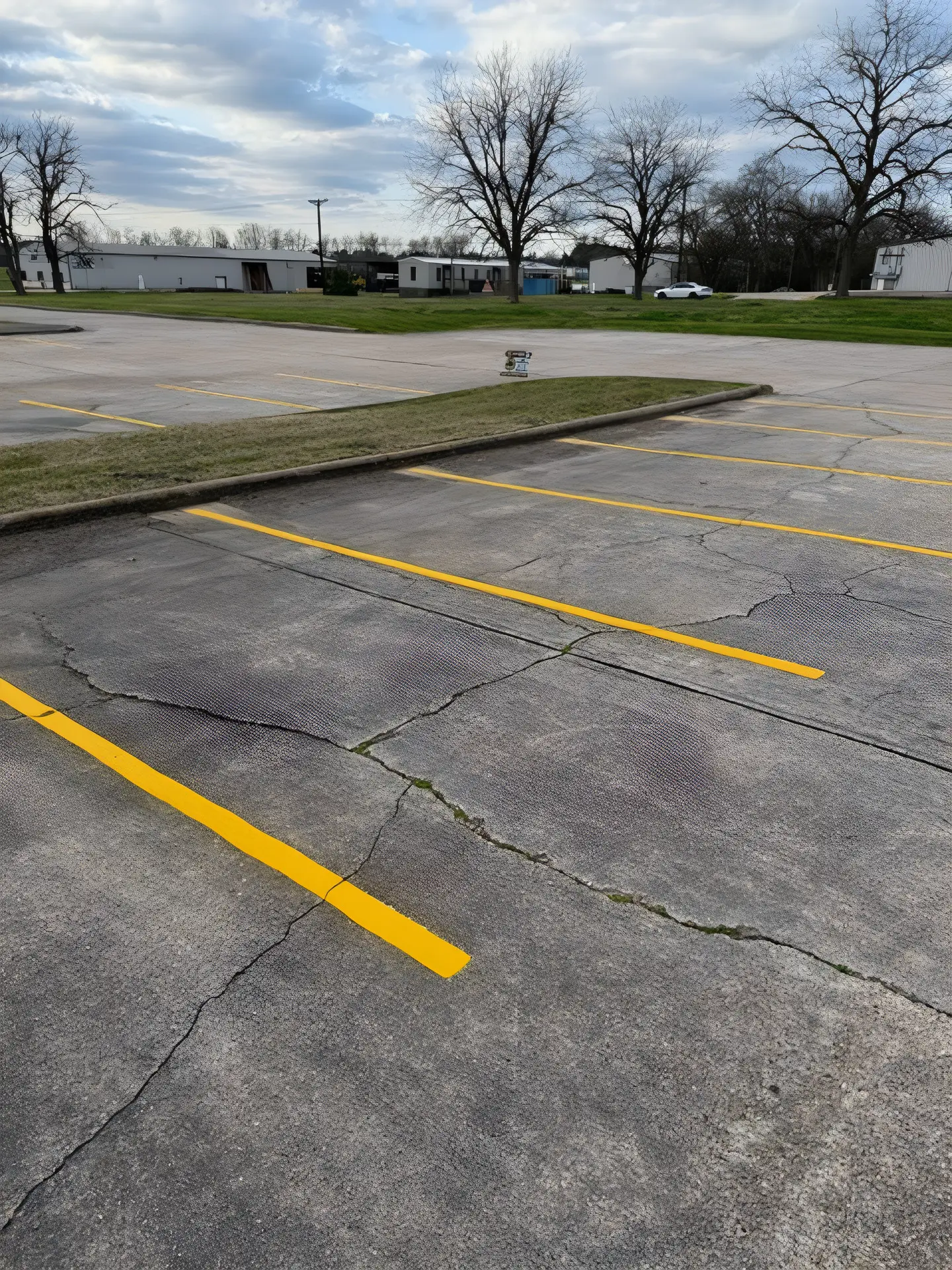 Cracked concrete parking lot with fresh yellow stall lines