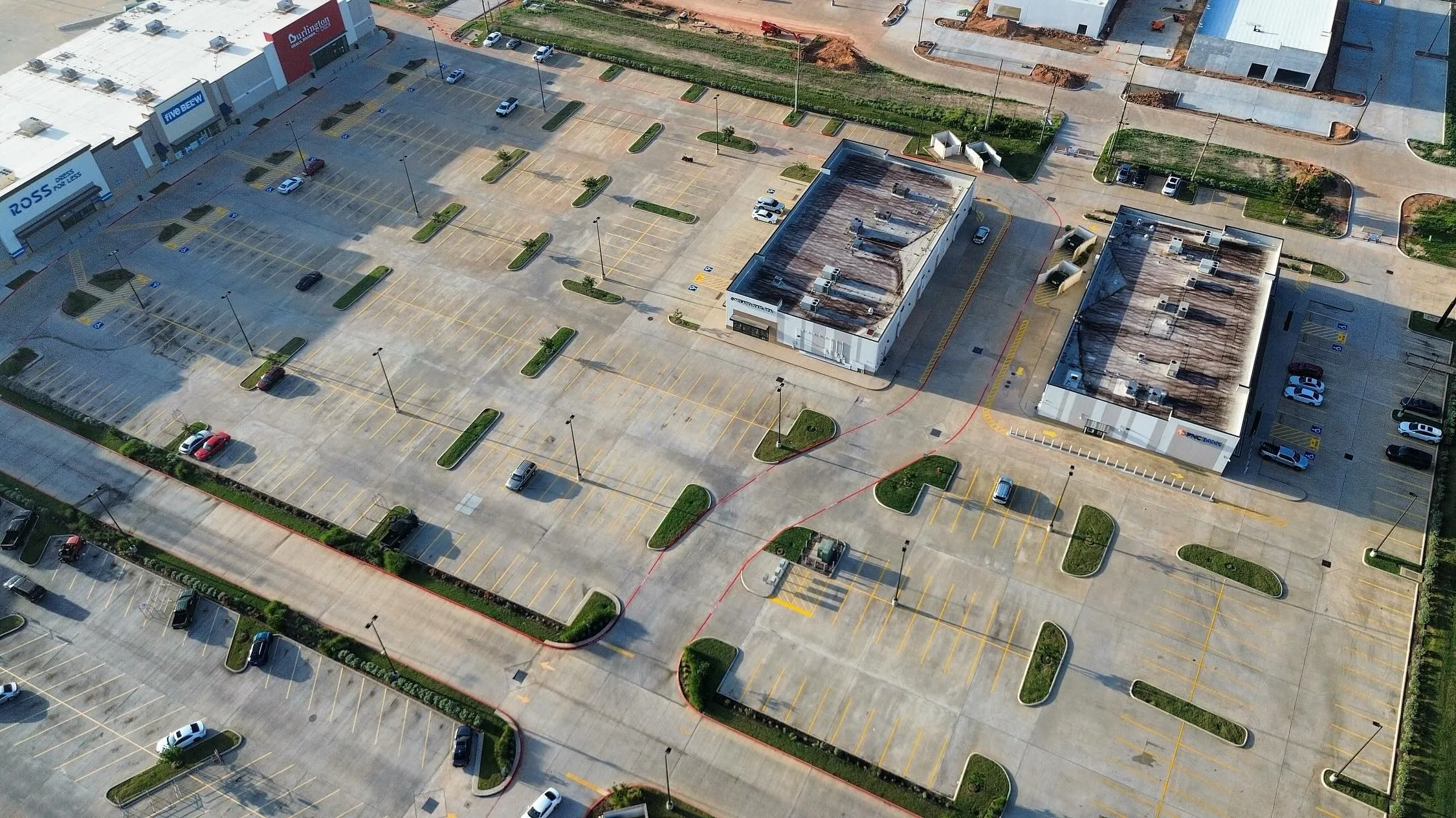 Aerial view of a shopping center lot with fresh yellow stalls and a red fire lane