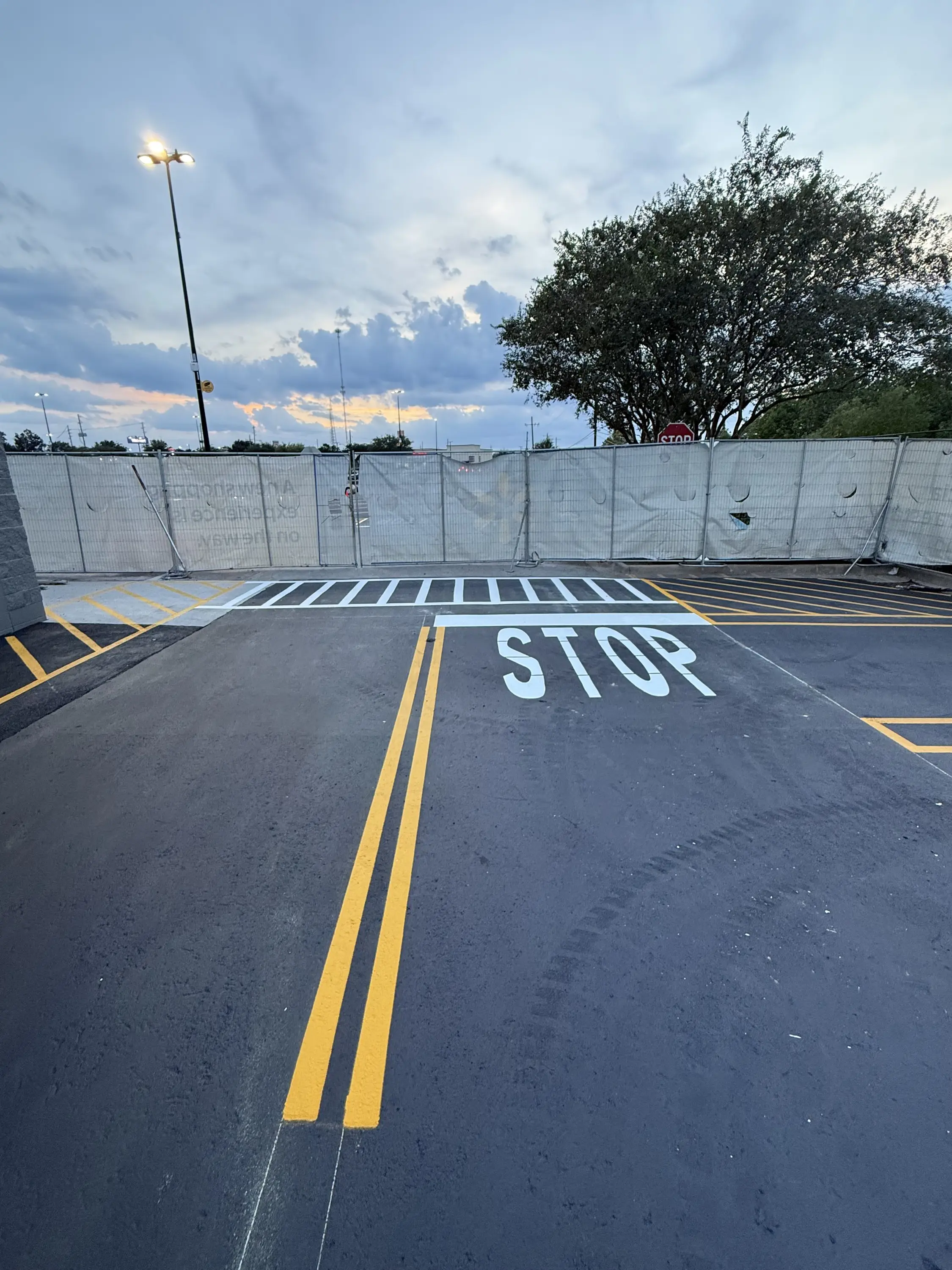 Jet-black sealed asphalt with a fresh yellow double line and a STOP stencil