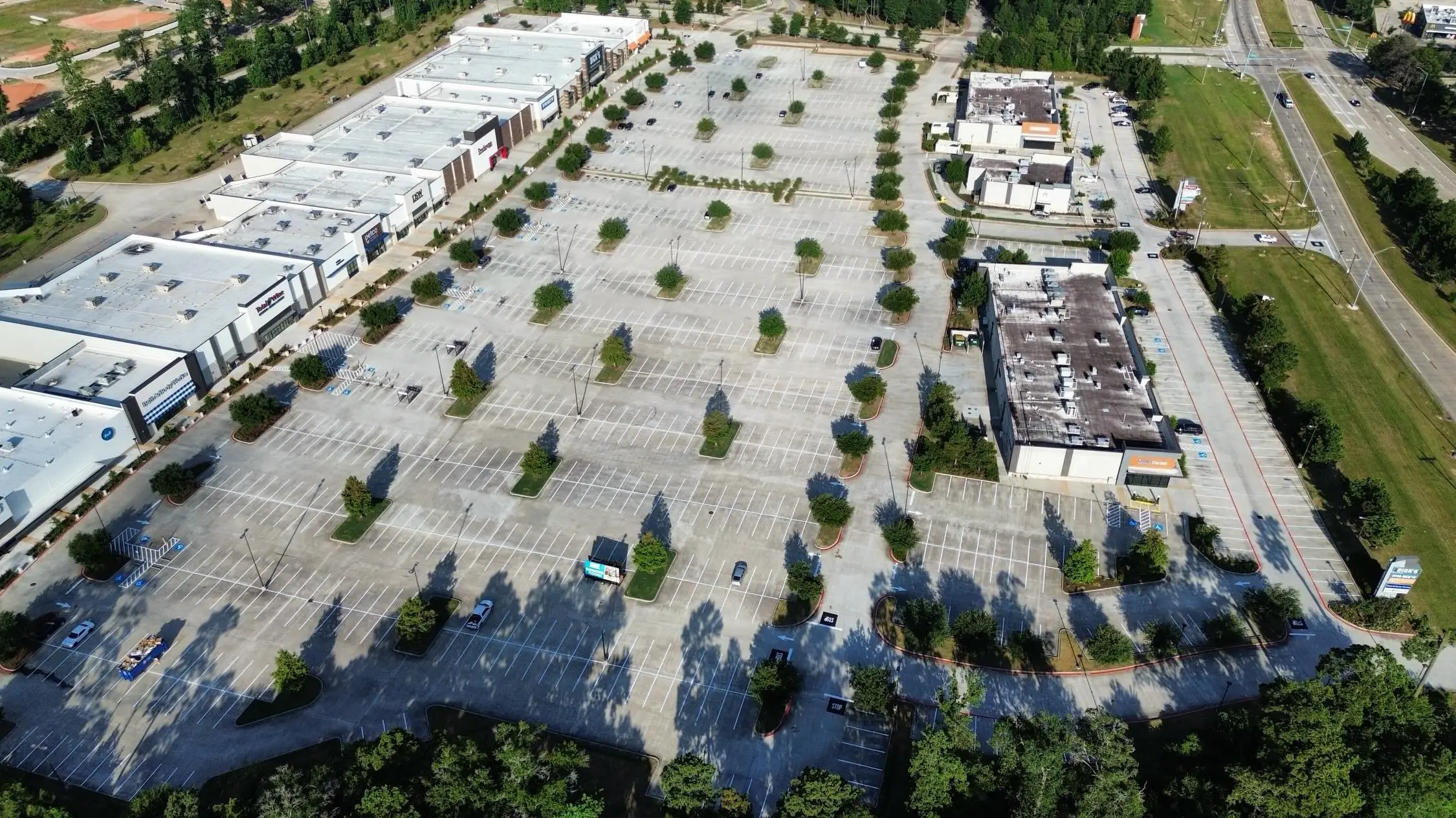 Aerial view of a large retail center parking lot with freshly striped stalls, landscaped islands, and marked drive aisles
