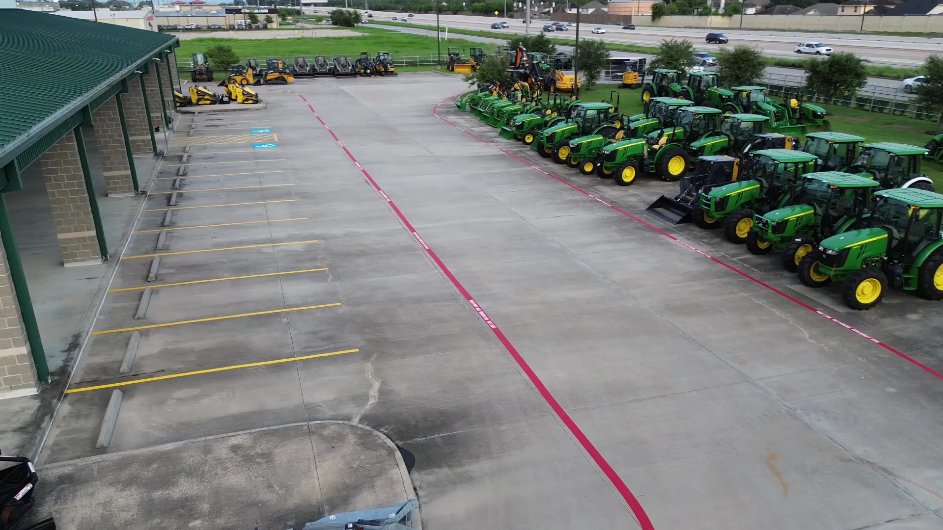 Rows of freshly striped stalls with concrete wheel stops at every space and a red fire lane curving through the lot