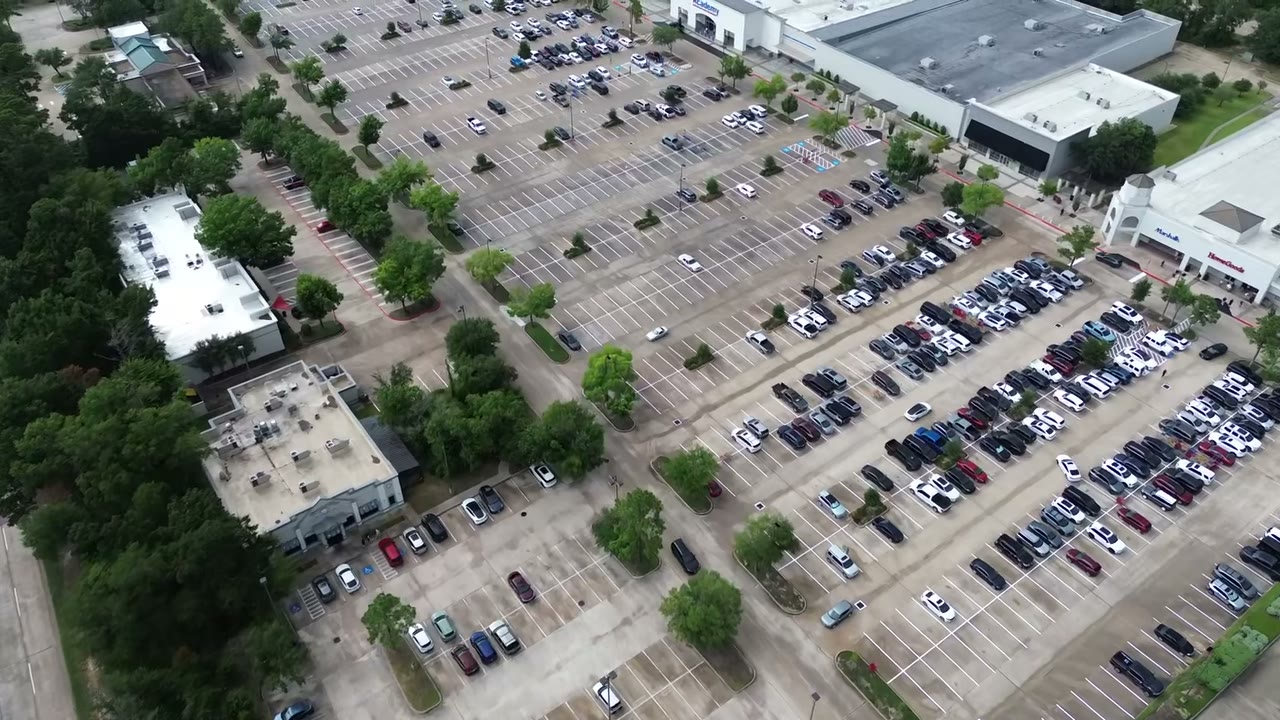 Aerial drone pass over a large Houston retail center parking lot, striped end to end by Coastal Roadworks